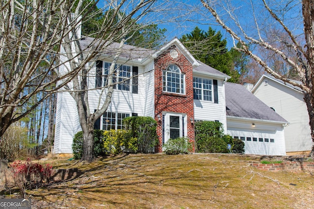 colonial-style house with a garage, brick siding, and a front yard