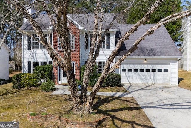 colonial home featuring a garage, concrete driveway, and a shingled roof