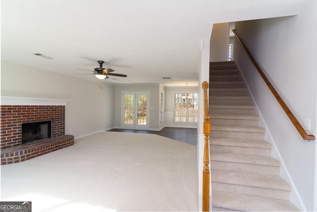 stairway featuring visible vents, crown molding, ceiling fan, baseboards, and a fireplace