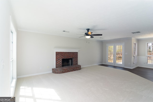 unfurnished living room featuring visible vents, a fireplace, crown molding, and french doors