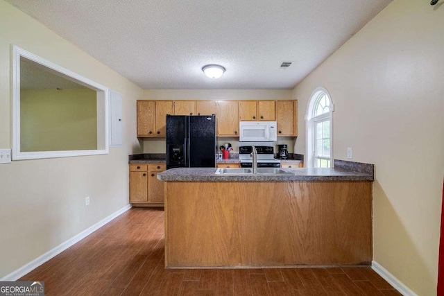 kitchen with white microwave, a peninsula, a sink, black fridge with ice dispenser, and dark countertops