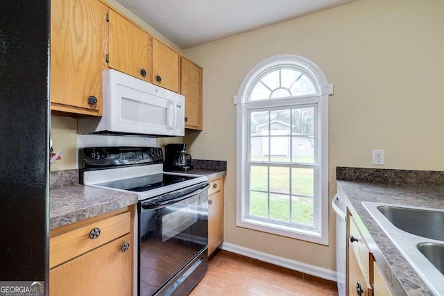 kitchen with a sink, black / electric stove, baseboards, white microwave, and dishwasher