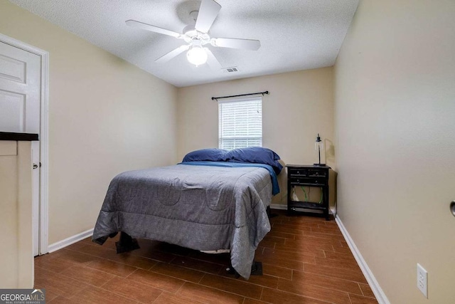 bedroom with visible vents, a textured ceiling, baseboards, and wood tiled floor