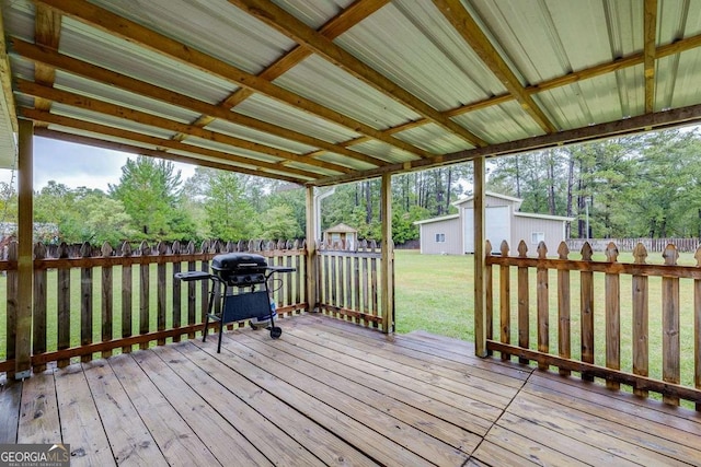 wooden deck featuring a lawn, a fenced backyard, an outdoor structure, a grill, and a storage unit