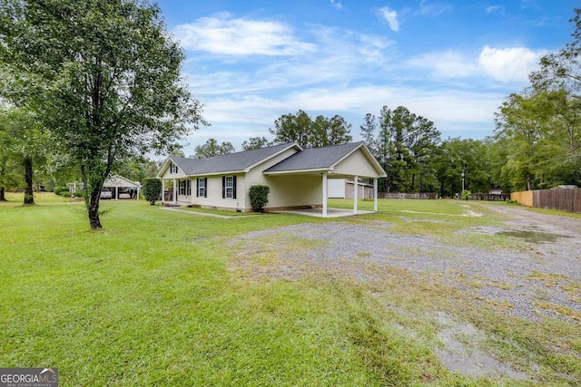 view of front facade with a carport, driveway, a front yard, and fence