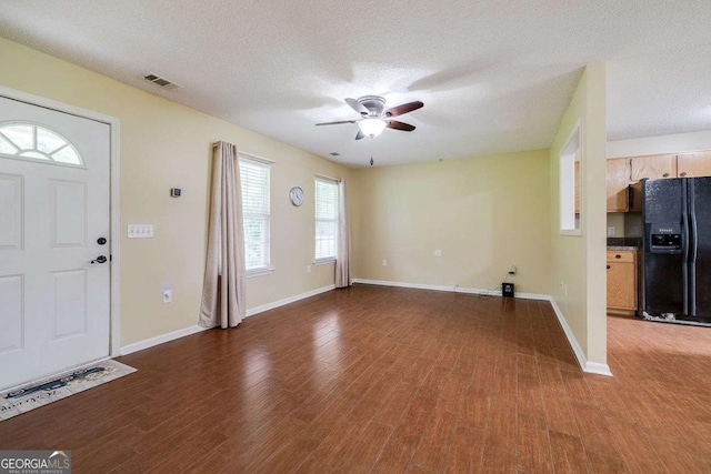 foyer entrance featuring visible vents, baseboards, a textured ceiling, and wood finished floors