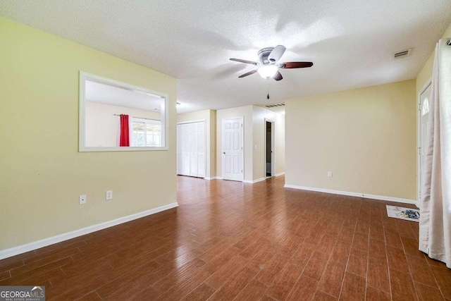 unfurnished room with a ceiling fan, wood finished floors, visible vents, and baseboards