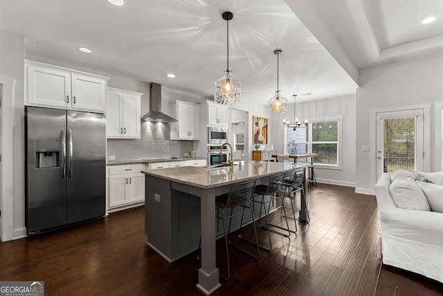 kitchen featuring a kitchen bar, decorative backsplash, stainless steel appliances, wall chimney exhaust hood, and dark wood-style flooring