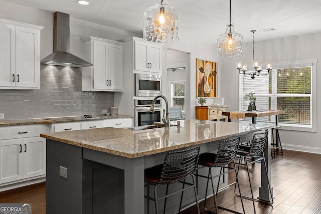 kitchen with visible vents, backsplash, dark wood-type flooring, wall chimney range hood, and appliances with stainless steel finishes