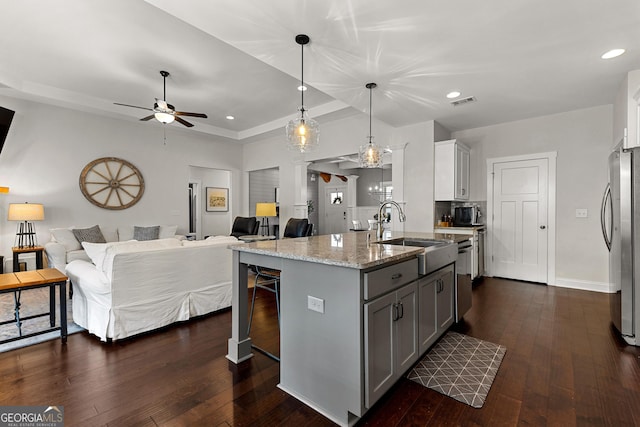 kitchen featuring a sink, gray cabinetry, open floor plan, stainless steel appliances, and dark wood-style flooring