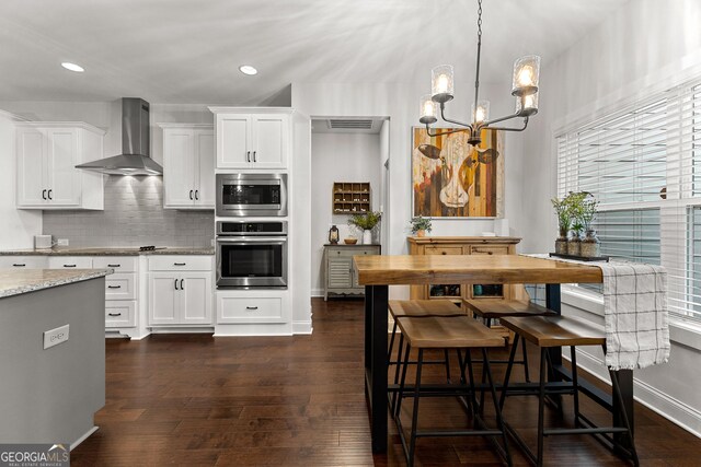 kitchen with tasteful backsplash, wall chimney range hood, a wealth of natural light, appliances with stainless steel finishes, and dark wood-style floors