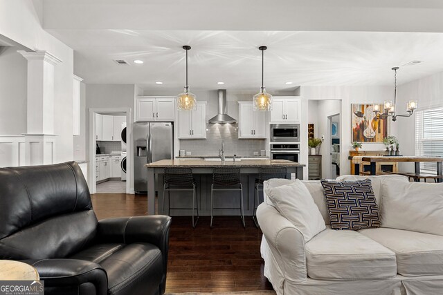 living area featuring dark wood-style floors, washer / clothes dryer, recessed lighting, decorative columns, and a chandelier