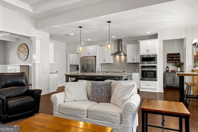 living room featuring recessed lighting, decorative columns, and dark wood-style flooring