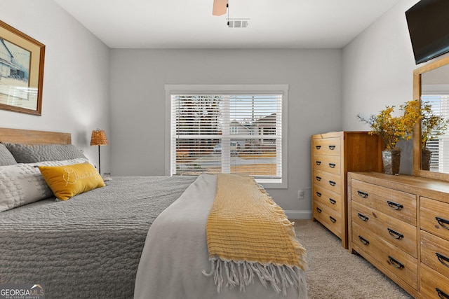 bedroom featuring visible vents, light colored carpet, a ceiling fan, and multiple windows