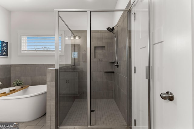 full bath featuring a freestanding tub, tile walls, and a stall shower