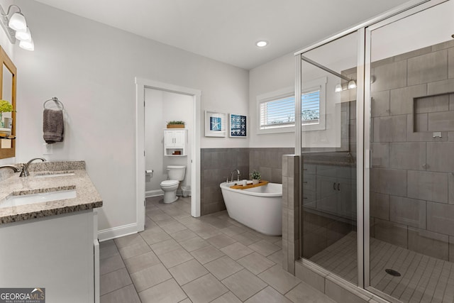 bathroom with tile patterned floors, toilet, a shower stall, double vanity, and a soaking tub