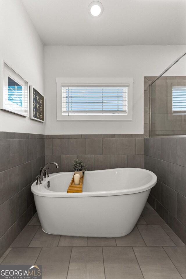 full bathroom with tile patterned flooring, wainscoting, a freestanding bath, and tile walls