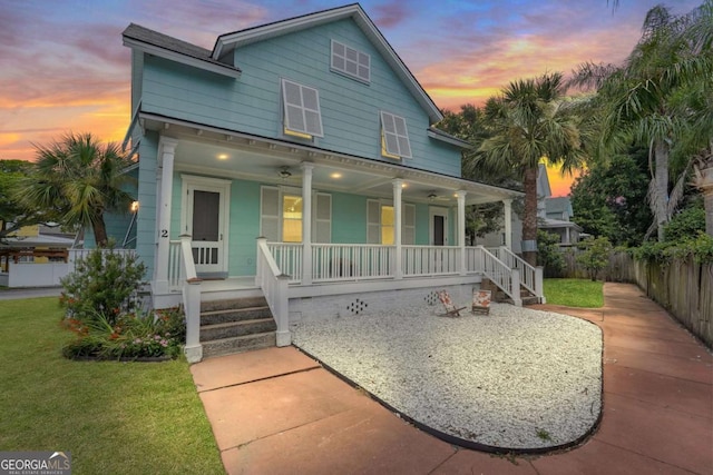 view of front of property with a porch, a front yard, and fence