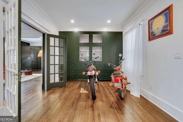 interior space featuring wood finished floors, crown molding, french doors, and baseboards