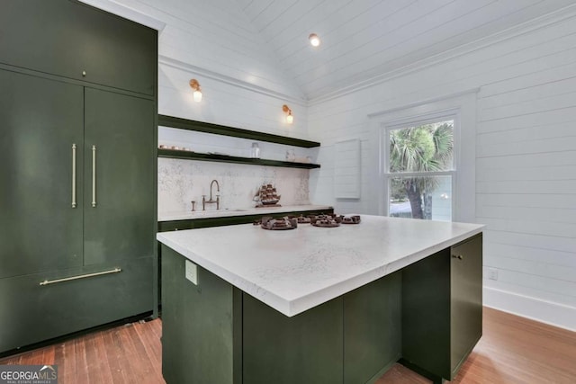 kitchen with a sink, green cabinets, vaulted ceiling, wood finished floors, and open shelves