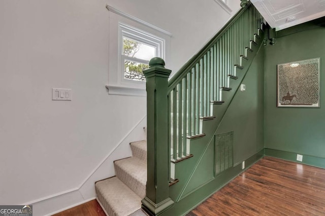 stairs featuring wood finished floors, visible vents, and baseboards