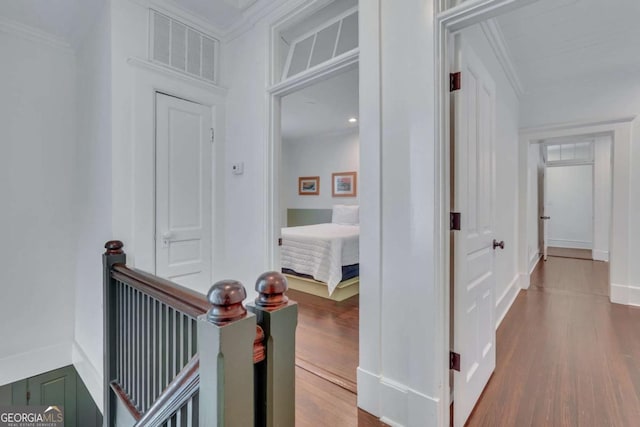 corridor featuring visible vents, crown molding, baseboards, and wood finished floors