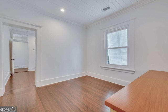 empty room featuring wood finished floors, baseboards, visible vents, recessed lighting, and crown molding