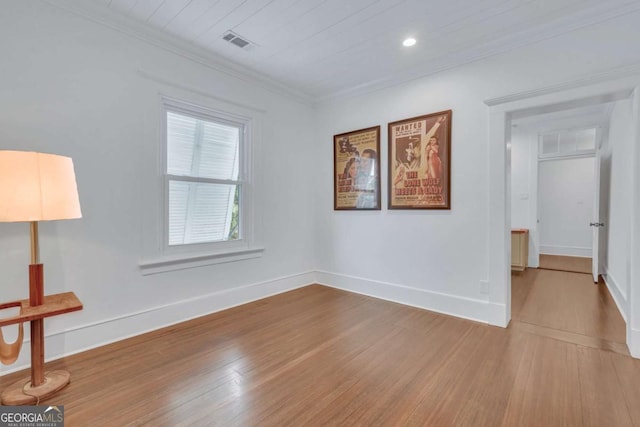 unfurnished room with crown molding, wood finished floors, visible vents, and baseboards