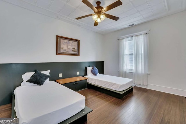 bedroom featuring a ceiling fan, wood finished floors, visible vents, and baseboards