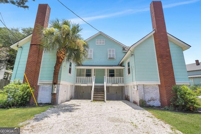 view of front of house with stairway, a chimney, covered porch, and driveway