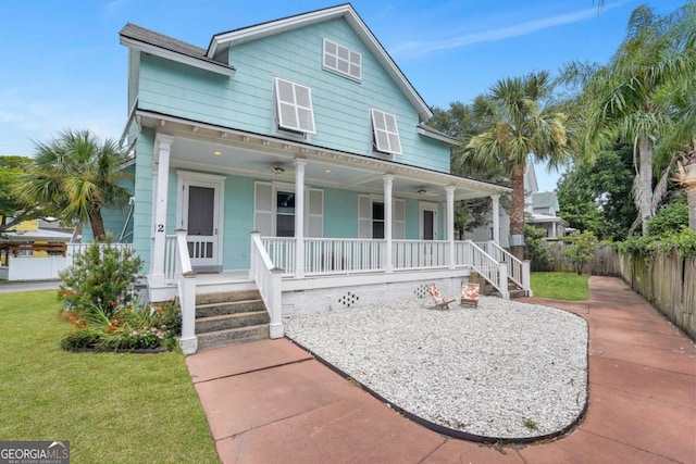 view of front of home with covered porch, a front lawn, and fence