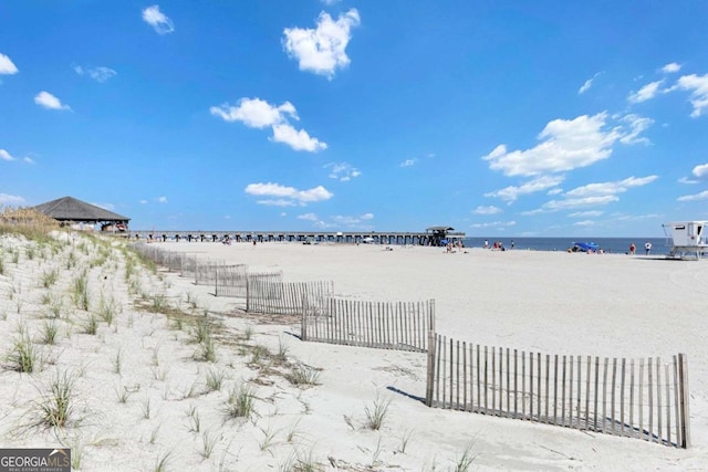 view of yard with fence, a beach view, and a water view