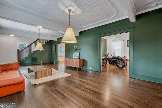 living area featuring stairway, wood finished floors, baseboards, an ornate ceiling, and crown molding