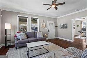 living room featuring ornamental molding, baseboards, and wood finished floors