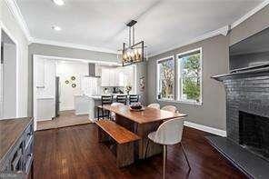 dining room with ornamental molding, an inviting chandelier, a fireplace, baseboards, and dark wood-style flooring