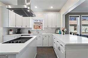 kitchen with decorative backsplash, white cabinets, a center island, and light countertops