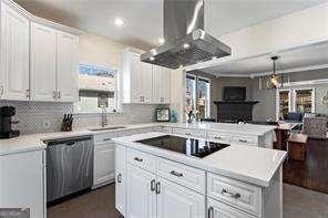 kitchen featuring black electric stovetop, dishwasher, light countertops, island exhaust hood, and white cabinets