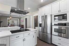 kitchen featuring recessed lighting, stainless steel appliances, light countertops, white cabinets, and wall chimney range hood