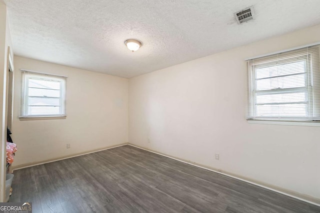 unfurnished room with visible vents, dark wood-style flooring, and a textured ceiling