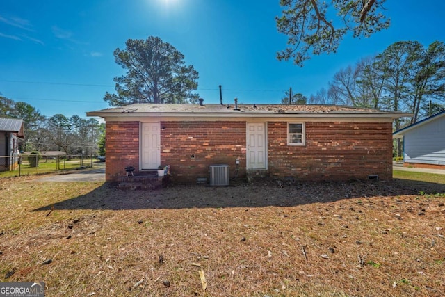 back of property featuring central AC unit, a yard, fence, and brick siding