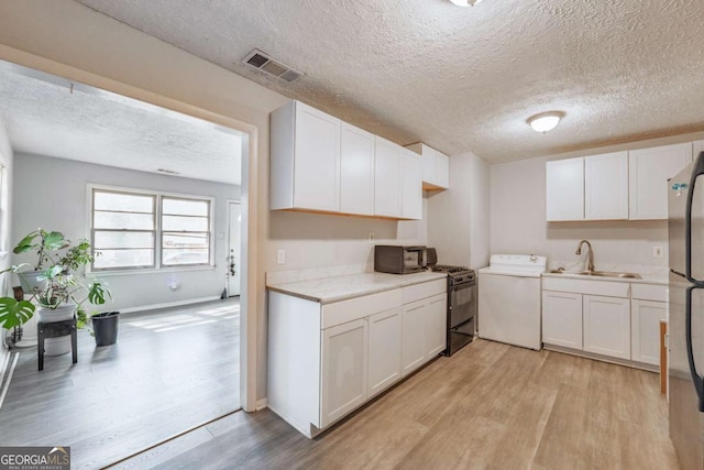 kitchen featuring light wood-style flooring, visible vents, black range with gas stovetop, and a sink