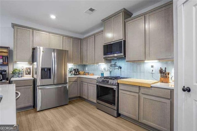 kitchen featuring tasteful backsplash, light wood-style floors, appliances with stainless steel finishes, and light countertops