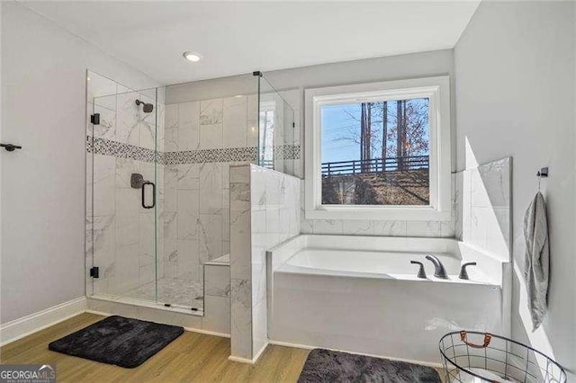 full bathroom with a shower stall, a bath, wood finished floors, and baseboards