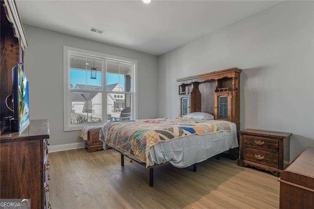 bedroom featuring wood finished floors, visible vents, and baseboards