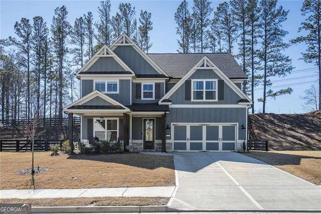 craftsman-style house featuring an attached garage, board and batten siding, driveway, and fence