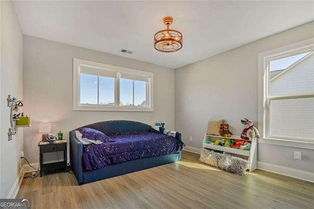 bedroom with wood finished floors, visible vents, and baseboards