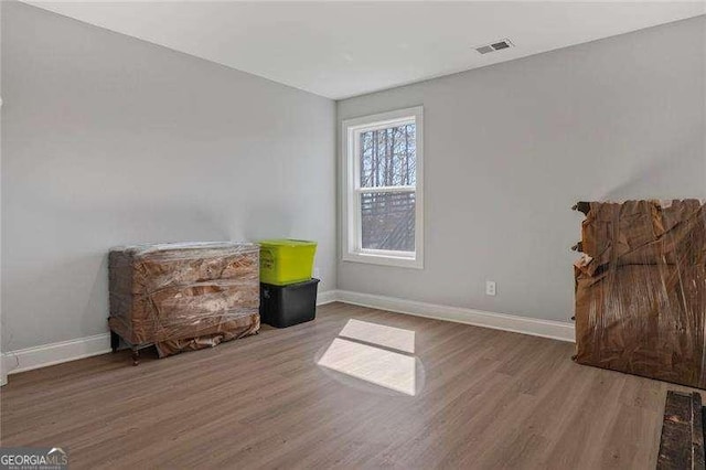 sitting room with wood finished floors, visible vents, and baseboards