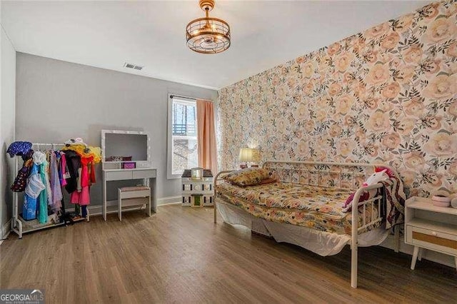 bedroom with visible vents, baseboards, and wood finished floors