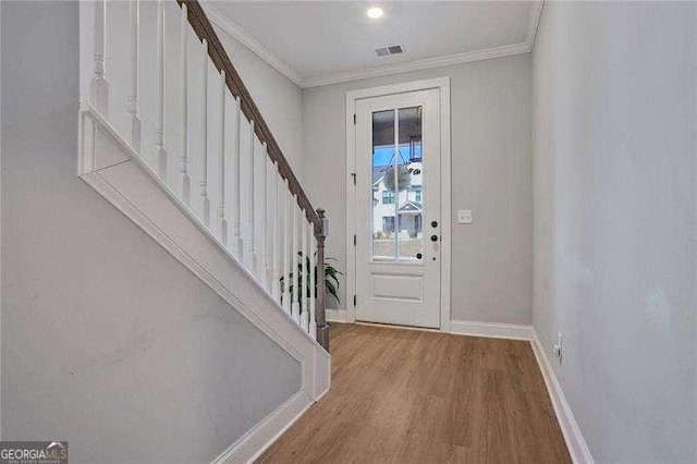 foyer with visible vents, ornamental molding, wood finished floors, stairway, and baseboards