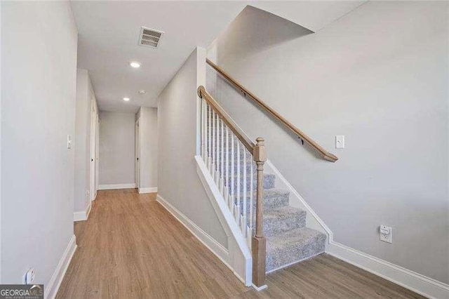 staircase featuring recessed lighting, visible vents, baseboards, and wood finished floors